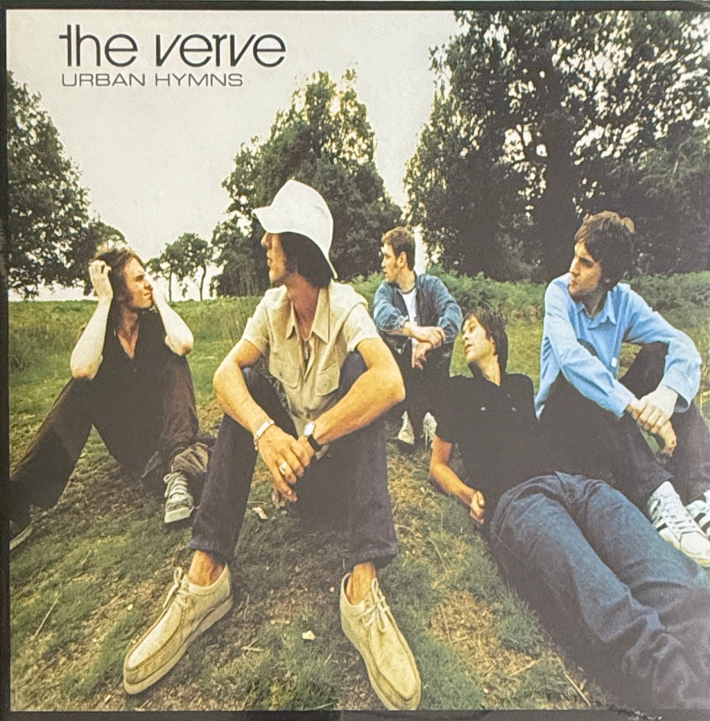 Album cover of 'Urban Hymns' by The Verve with five people sitting on grass.